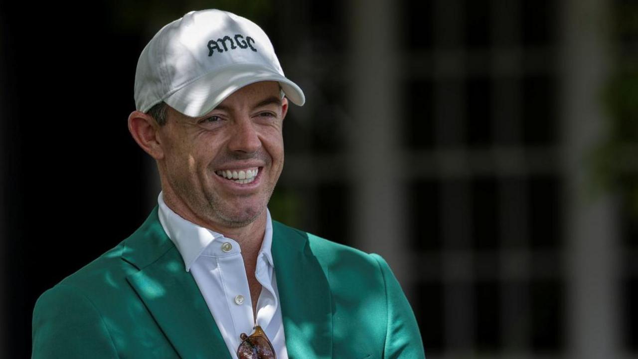 Rory McIlroy smiles as he talks to Augusta officials on his return to the Masters