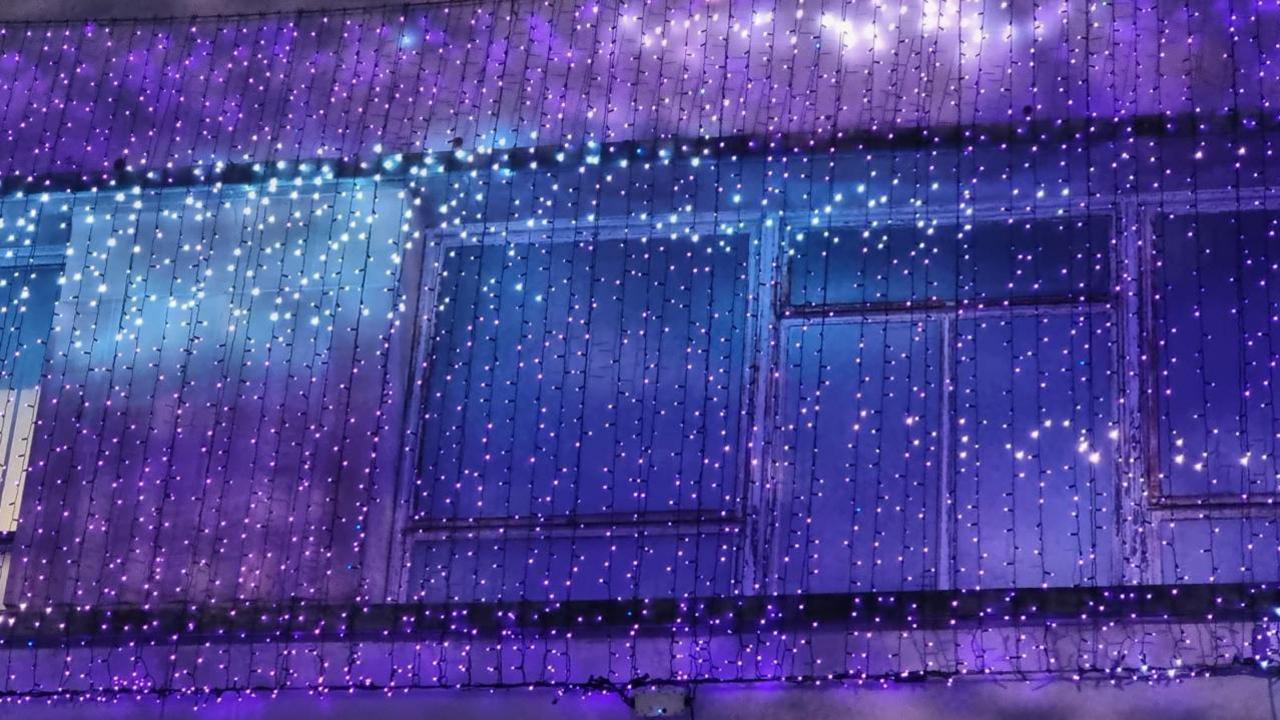 Purple and blue string Christmas lights draped over the front of a building. 