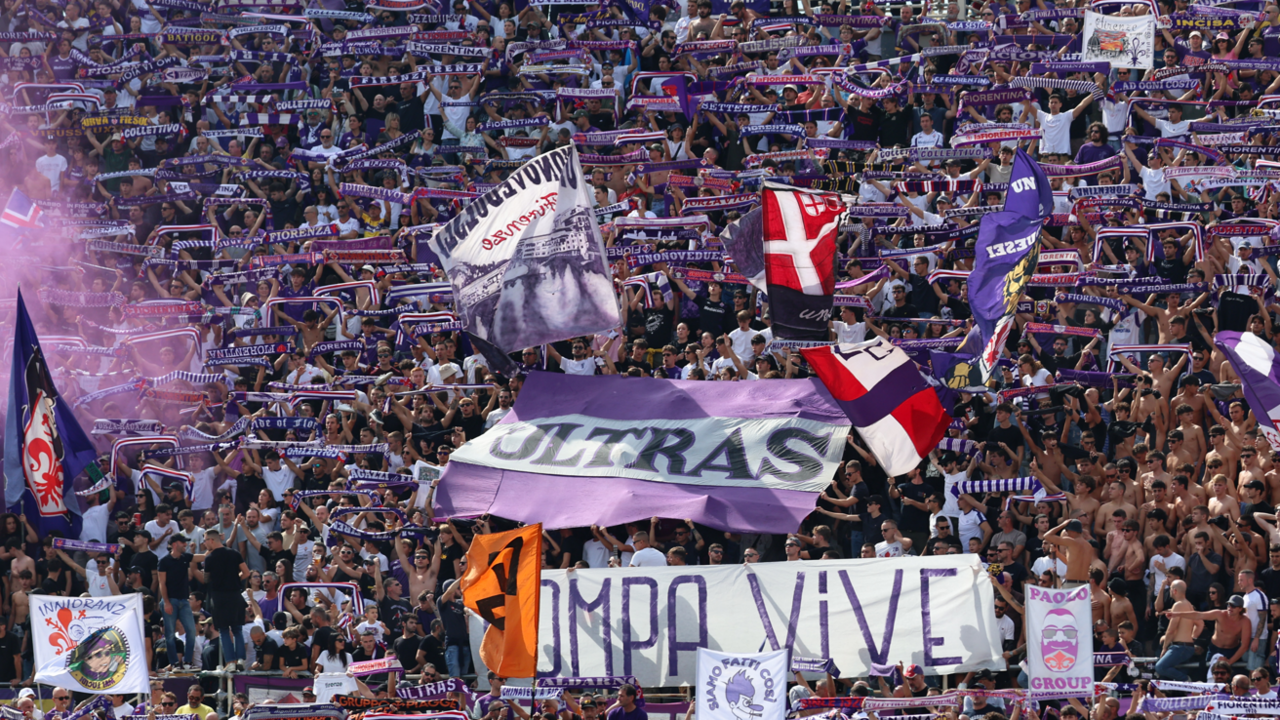 A large crowd of Fiorentina fans, waving flags and holding scarves above their heads