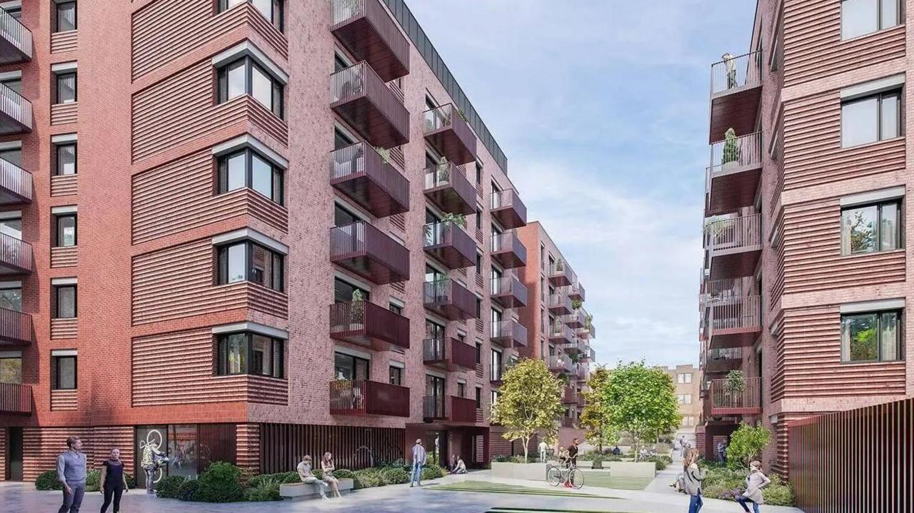 An architect's design of the proposed development. Brown/red coloured flats with balconies line either side of a shared precinct with trees and benches. A few people wander around or sit down.