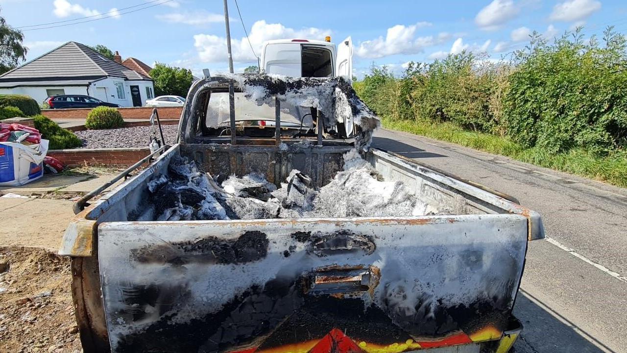 The burnt-out vehicle taken from the back of the car and showing the pick-up style vehicle badly damaged by flames and just the shell of it remaining