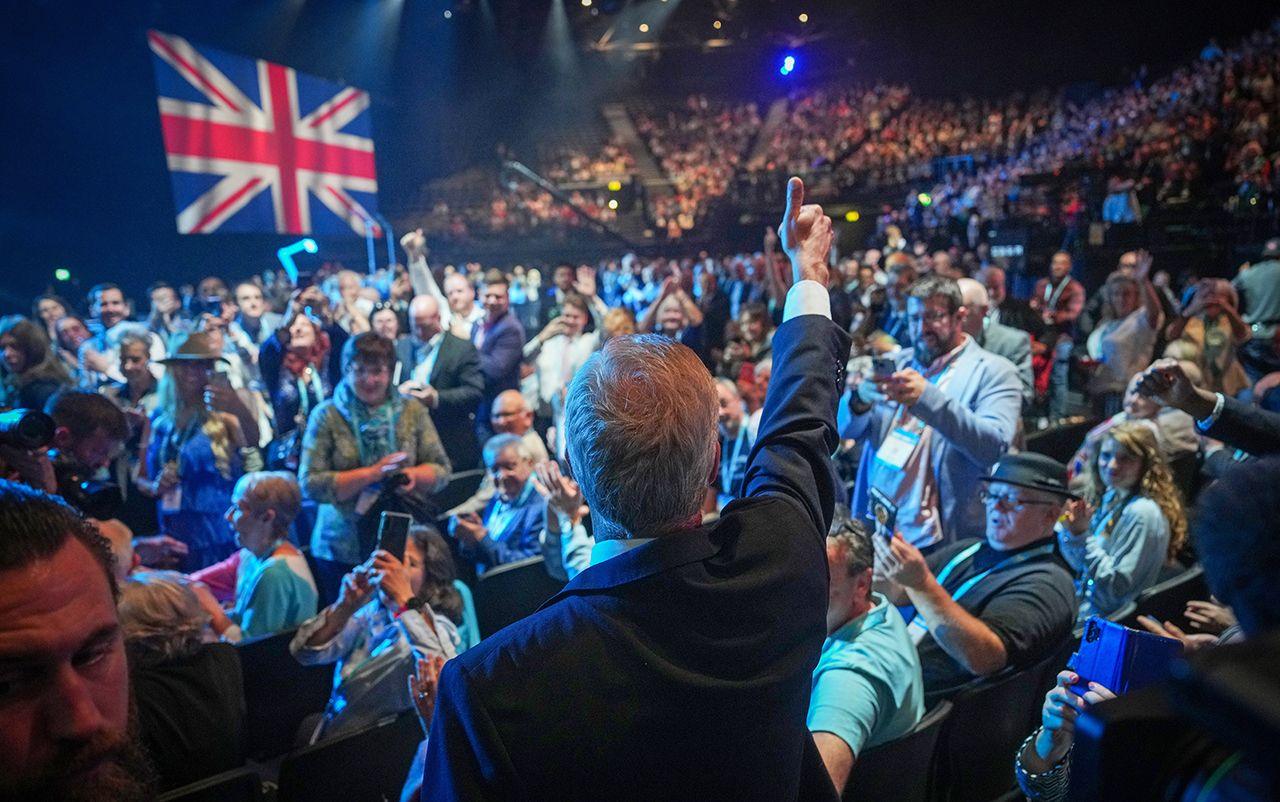 Nigel Farage is photographed from behind, as he gives a thumbs up in front of a large crowd and a big union flag in the National Exhibition Centre in Birmingham on 20 September