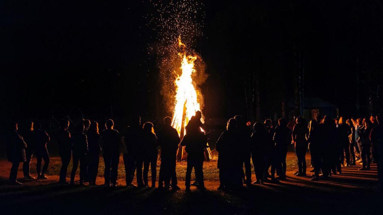 Stock photo of a big group of people standing in front of a bonfire