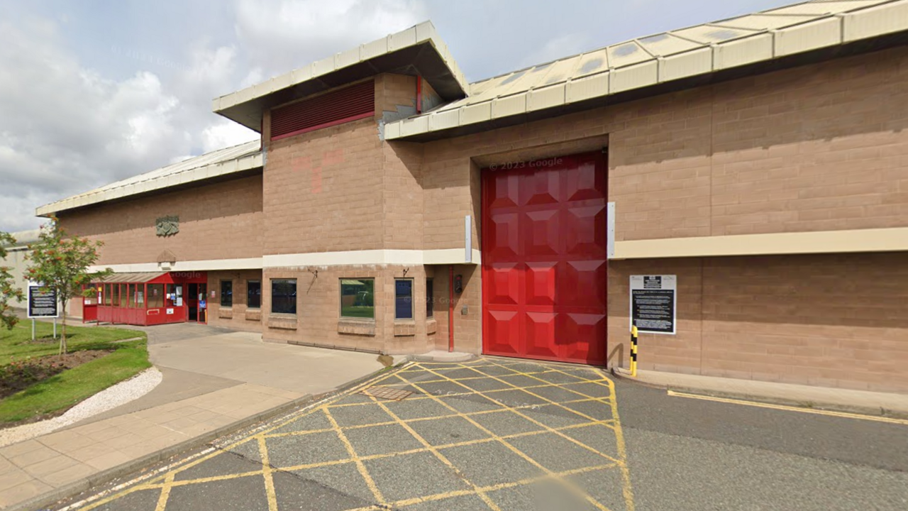 A front view of HMP Holme House. It is a brick building with  large red door