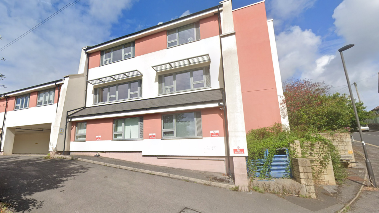 A salmon pink and white building sits set above a busy road in Bath in Somerset