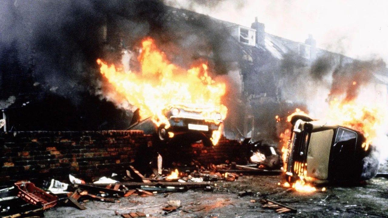 Upside down car on fire in what appears to be the aftermath of a bombing