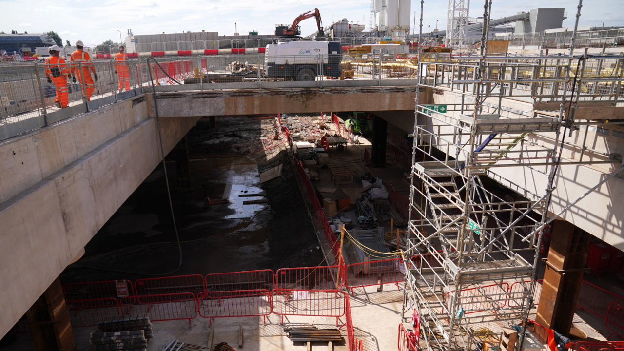 A general view of the HS2 site at Old Oak Common, in west London, showing a concrete underpass with metal scaffold tower on the right from the ground up, and on the bridge section, there are three workers in orange hi-vis suits. A yellow crane can be seen in the background and the London skyline of buildings. Picture date: Thursday August 10, 2023.