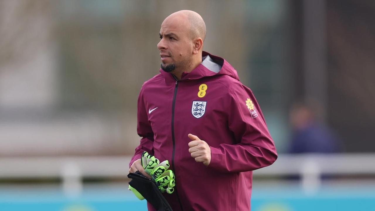 Fahd is wearing an England jacket and holding green gloves