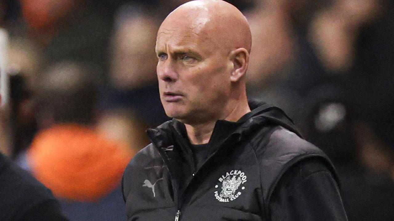 Steve Agnew watches on during a Blackpool game wearing a club gilet