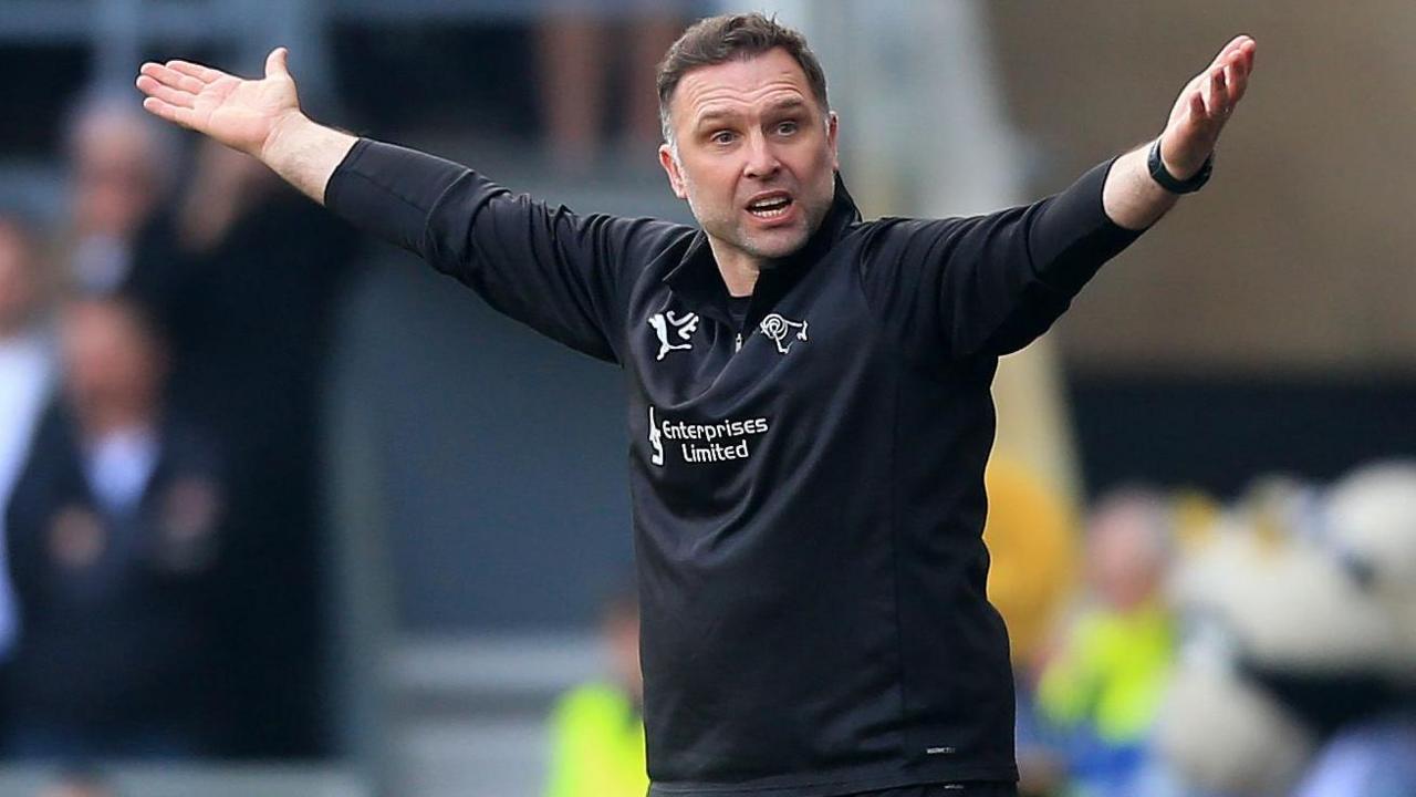 John Eustace raises his arms in the air