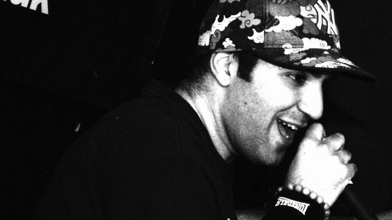 A black and white photo of a man in a hat. He is side on to the camera.
