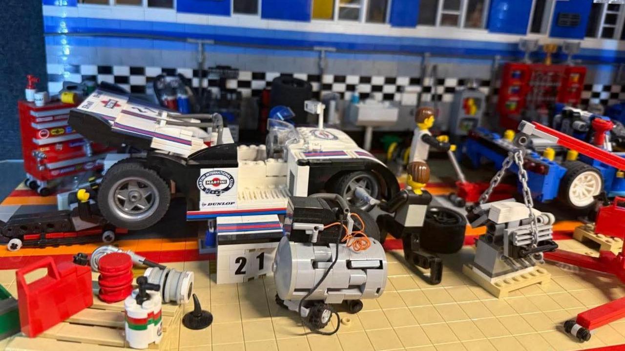 A Lego display showing a car in a garage, with a mechanic working on it and various tools and equipment.