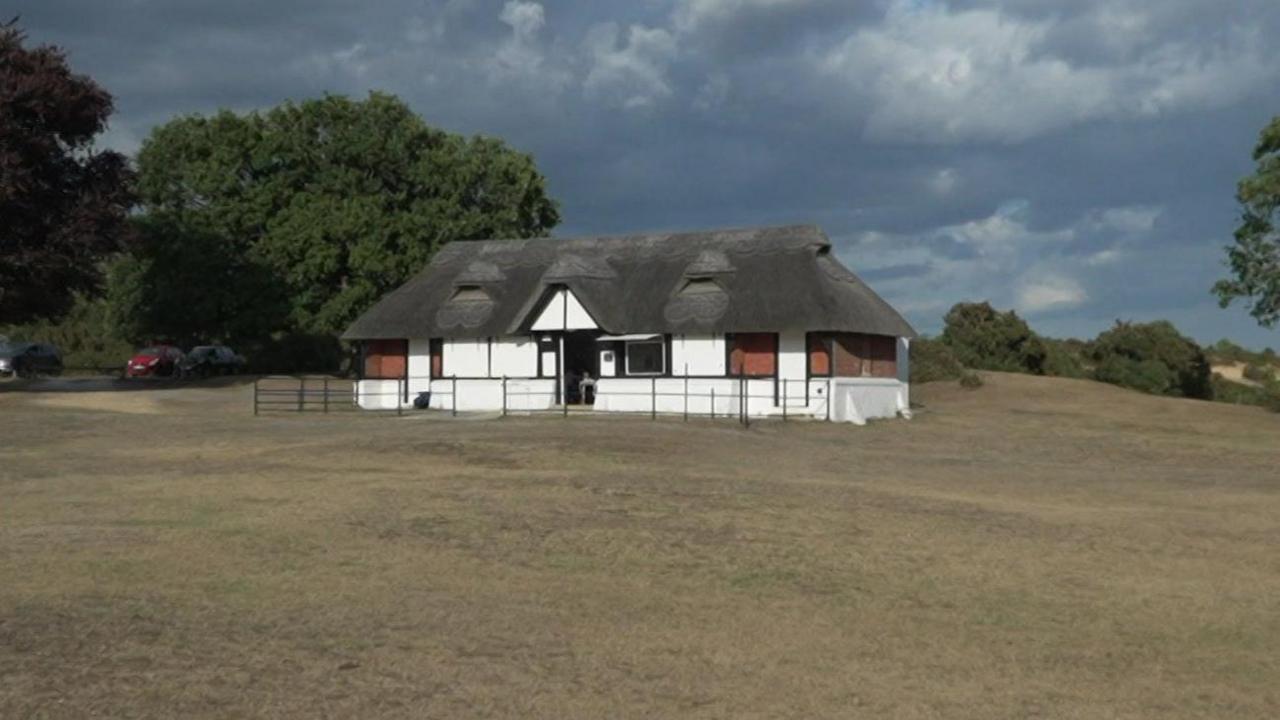 The clubhouse is Tudor-esque in appearance, complete with a thatched roof, set amid a park.
