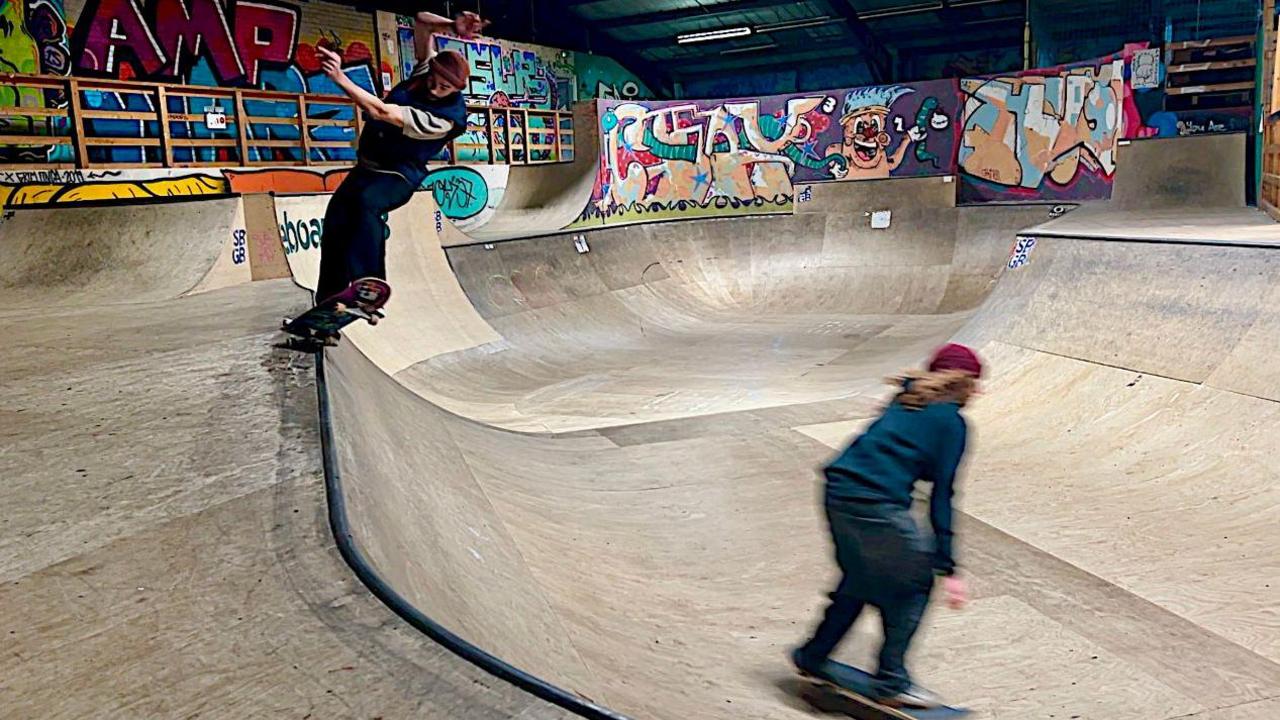 Two skateboarders are shown in action at the skatepark