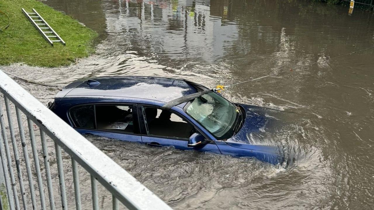 Blue car submerged in floodwater