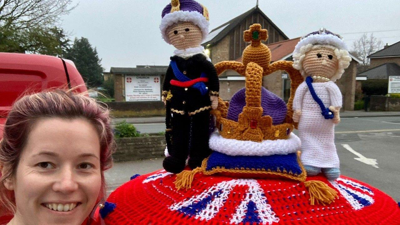 A knitted Queen and Prince Philip stand either side of a knitted crown on this topper.  