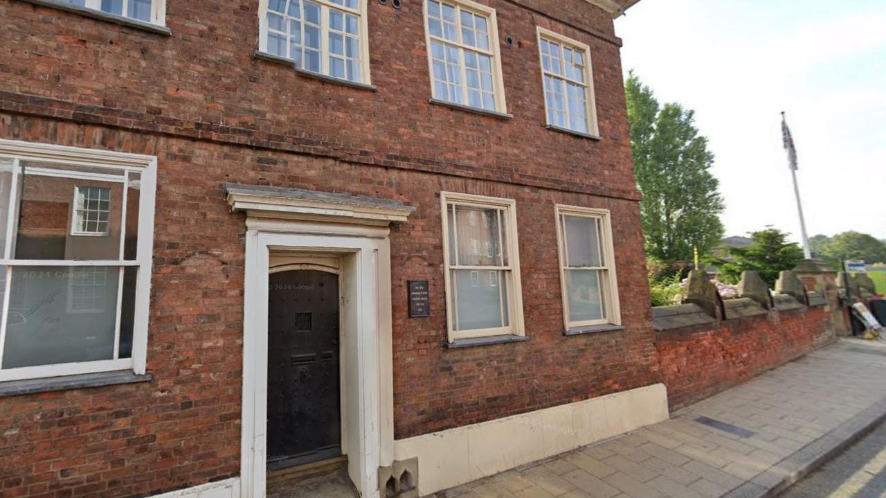 The front of the Schoolmaster’s House in St John Street. A plaque by the door reads "The Old Grammar School Master's House, erected 1682".