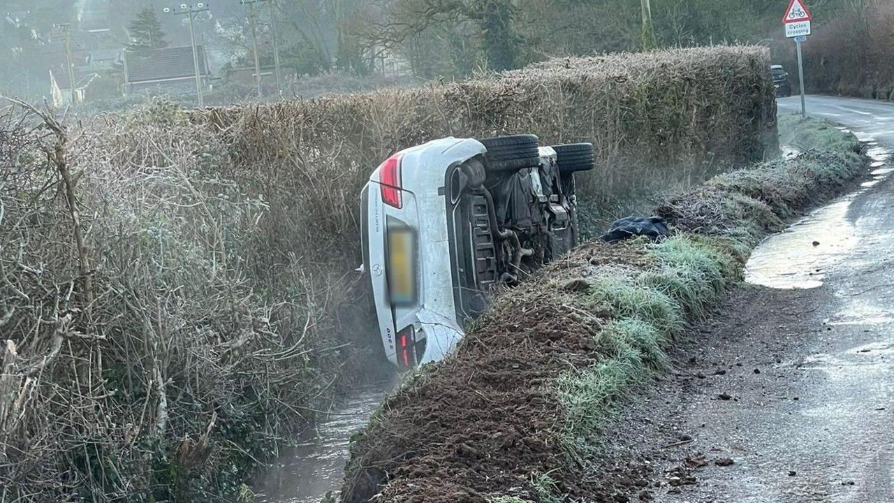 A white car overturned on its side in a river