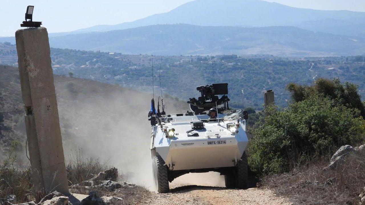 An Irish Defence Forces vehicle in Lebanon from media update on 14 October 2024.  A soldier is driving a white military vehicle along a dusty road with a panoramic view of mountains behind 