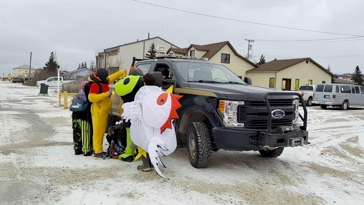 Children in Halloween fancy dress speaking with polar bear alert rangers, who are guarding the town