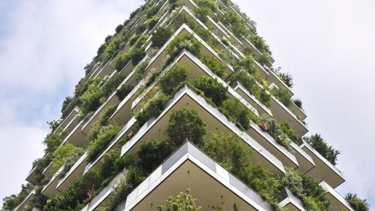 A vertical tower with balconies and lots of plants. It is high in the sky against a blue sky background with some clouds. CGI image. 