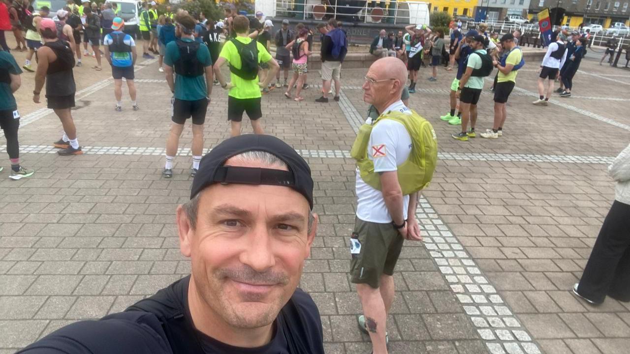 Graham takes a selfie in front of a group of runners waiting to start a race