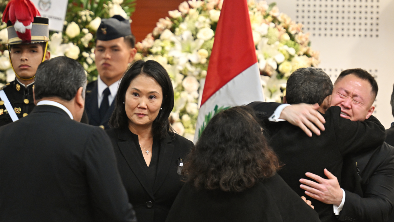 Keiko and Kenji Fujimori, children of late Peru's former president Alberto Fujimori, accept condolences from relatives during. Kenji, to the right, can be seen receiving a hug as he cries. Keiko to the left and centre of the image shakes the hand of a man who has his back to the camera