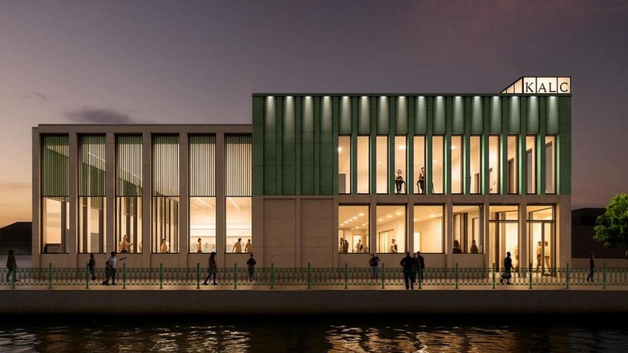 An artist's impression of how the new leisure centre on Hove seafront will look. A square building with large windows is lit up, with water in front and a sunset behind