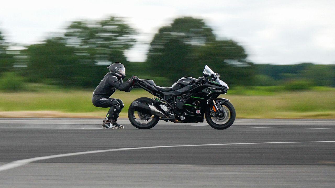 Jonny Davies in a helmet and black motorcycle gear being dragged behind a motorbike at a world record attempt test