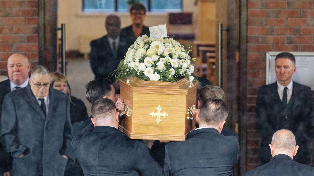 A coffin carrying the body of snooker player Terry Griffiths is borne by pallbearers into  Llanelli Crematorium