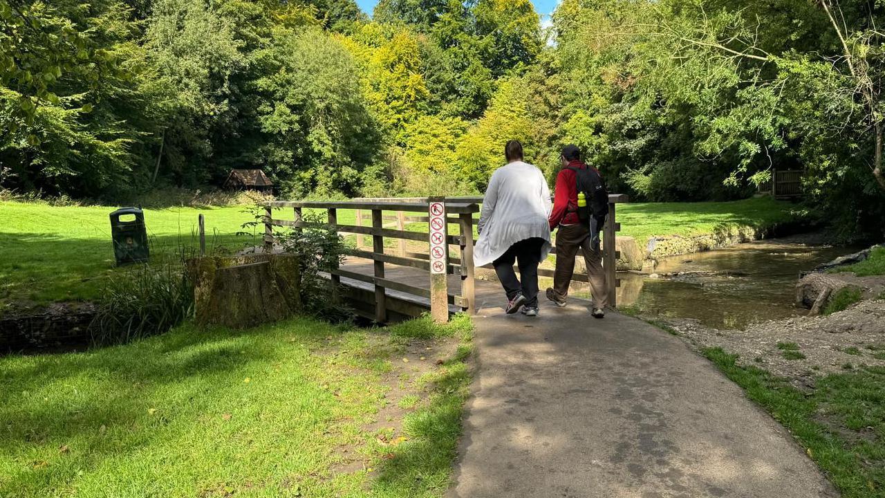 A couple walking towards a bridge over the River Lud at Hubbarb's Hills in Louth