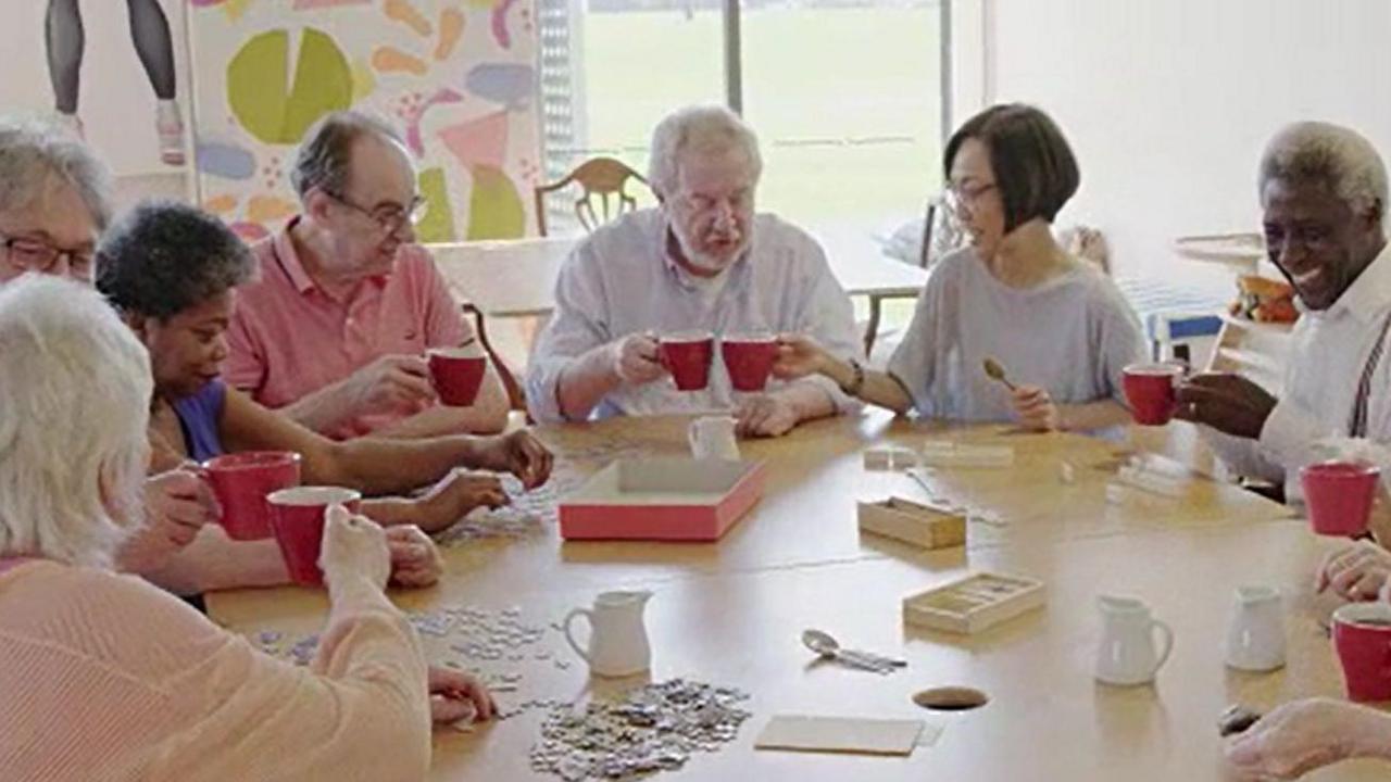 A group of older people enjoy a cup of tea around a table at a day centre