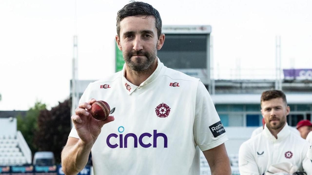 Ben Sanderson carrying the match ball after taking 7-31 against Worcestershire