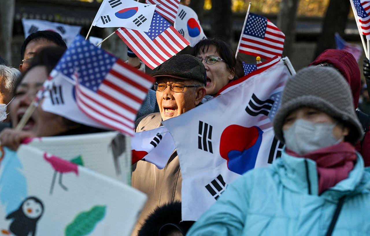 A group of men and women waving South Korean and US flags gather in Seoul to show support to the president on Wednesday