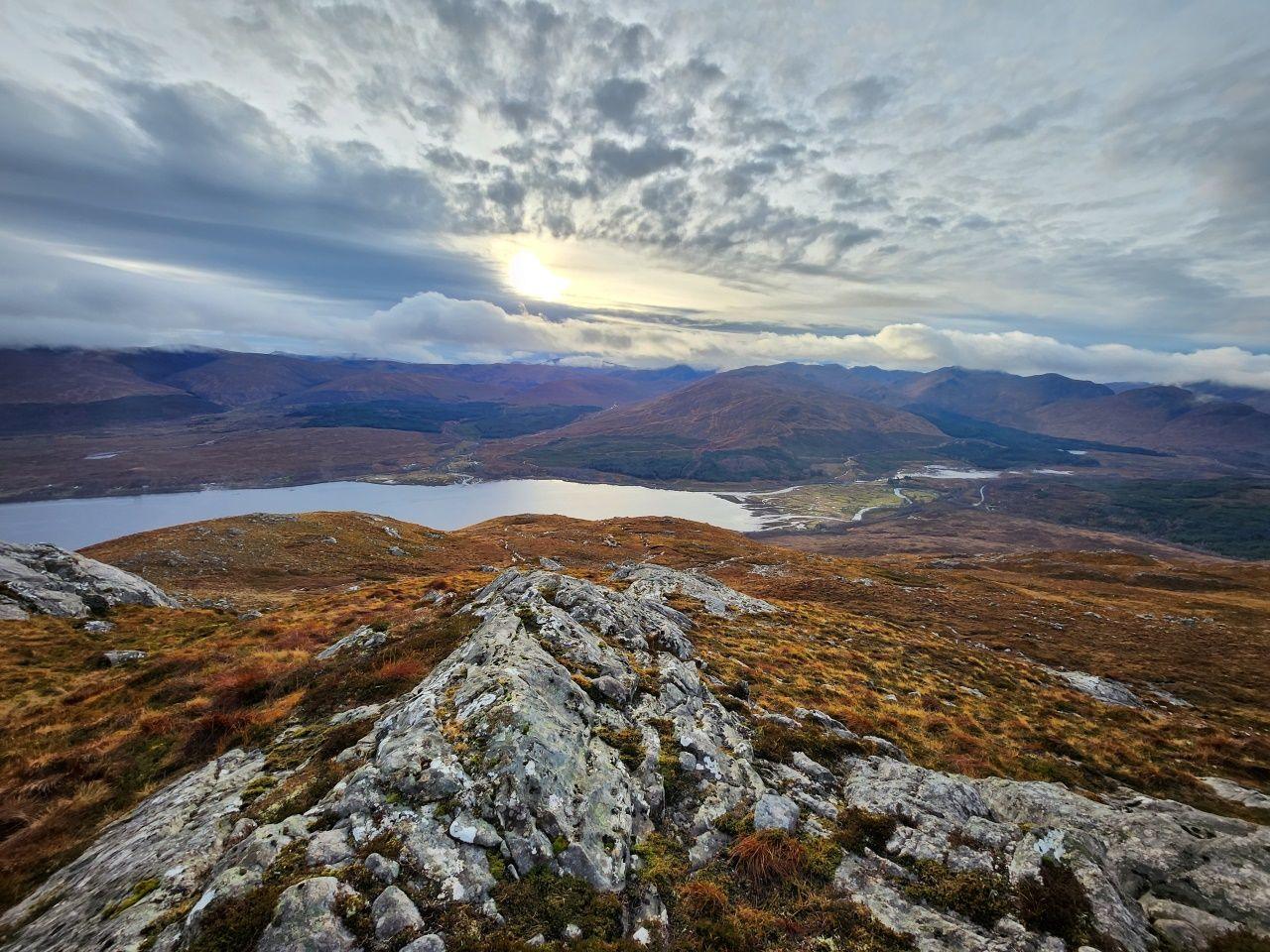 A landscape with a loch in the middle taken from a hill