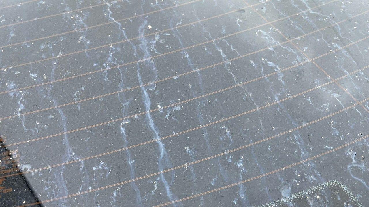 The rear window of a car showing white, streaky stains and chalky residue.