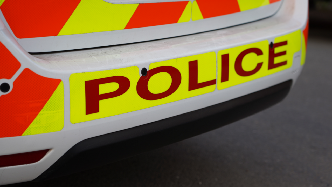 The rear of a police car, with the word 'POLICE' in red letters against a yellow background