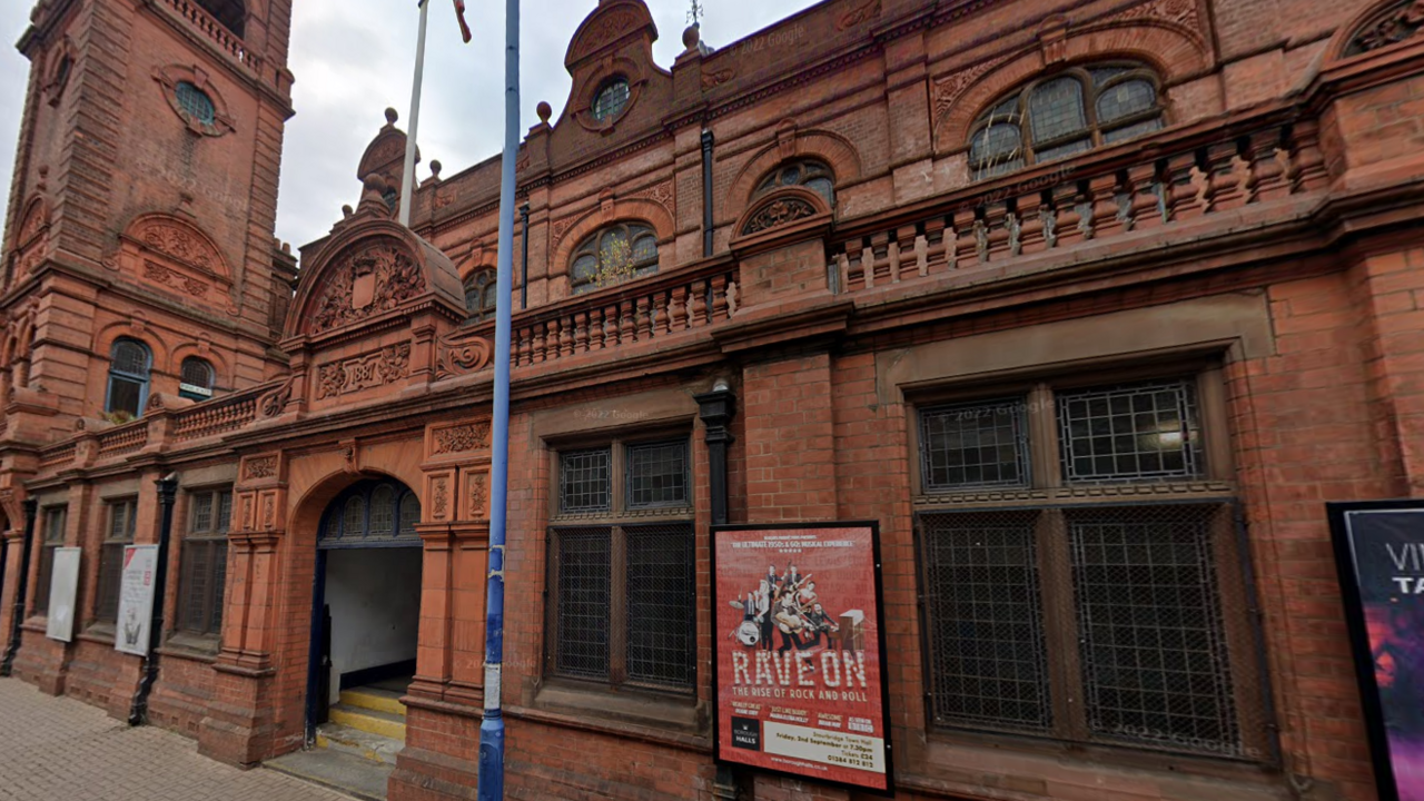 Exterior of Stourbridge Town Hall, a red-brick building with advertising posters for shows visible