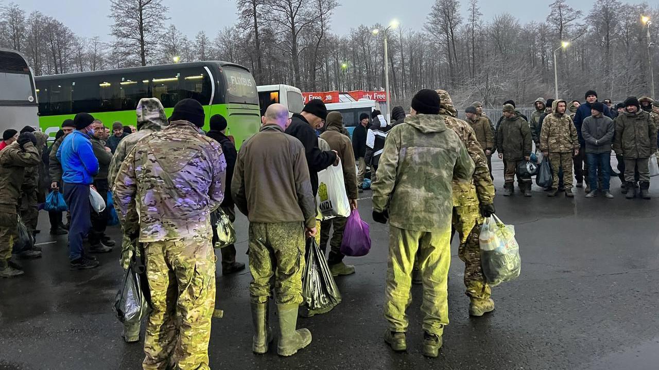 Russian soldiers in uniform and winter clothing gather near coaches