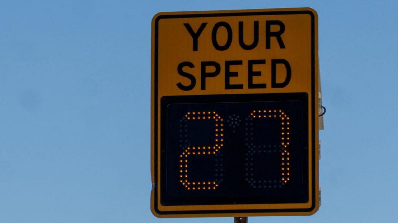 A speed sign that tells drivers what their speed is while they are driving. It is yellow, and reads "Your Speed: 27"