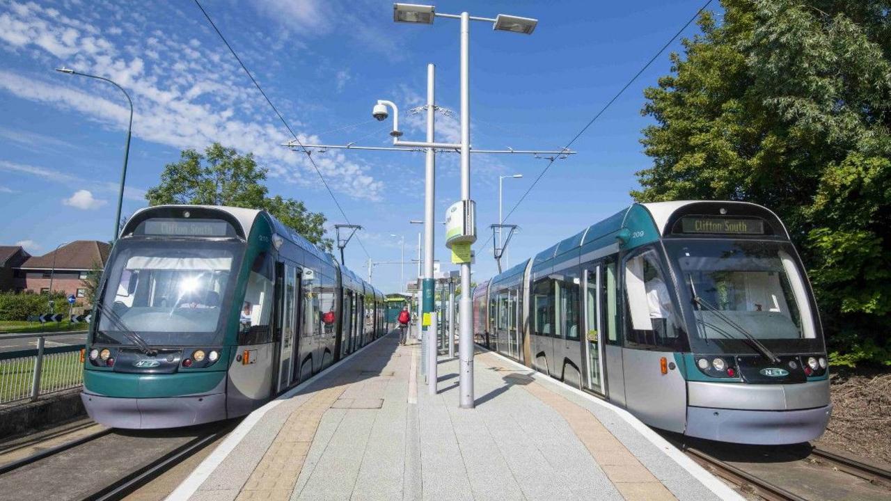 Two trams sitting at platforms at a station