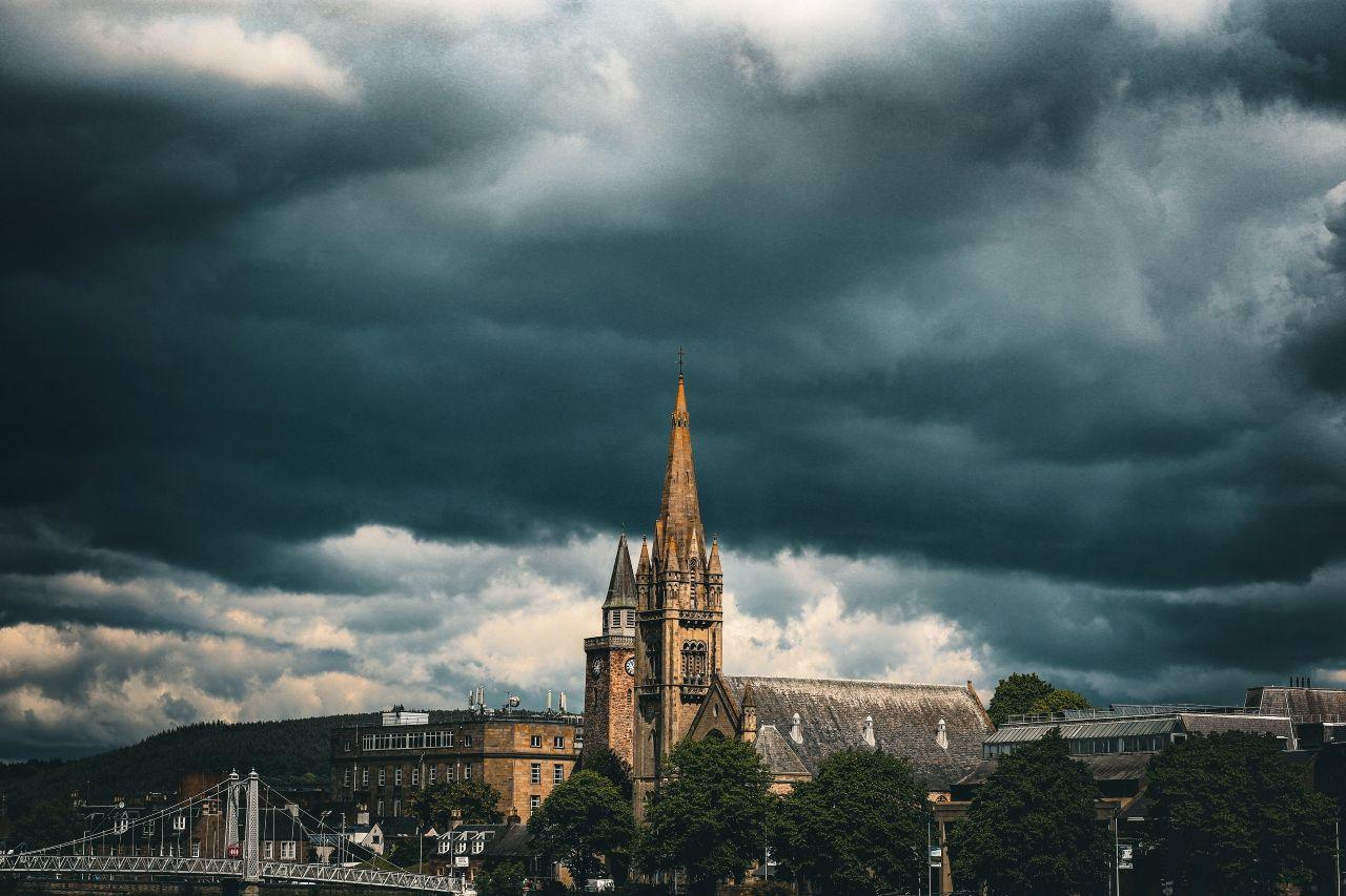 A dark, brooding cloudy sky over a city centre, with a church steeple in the middle