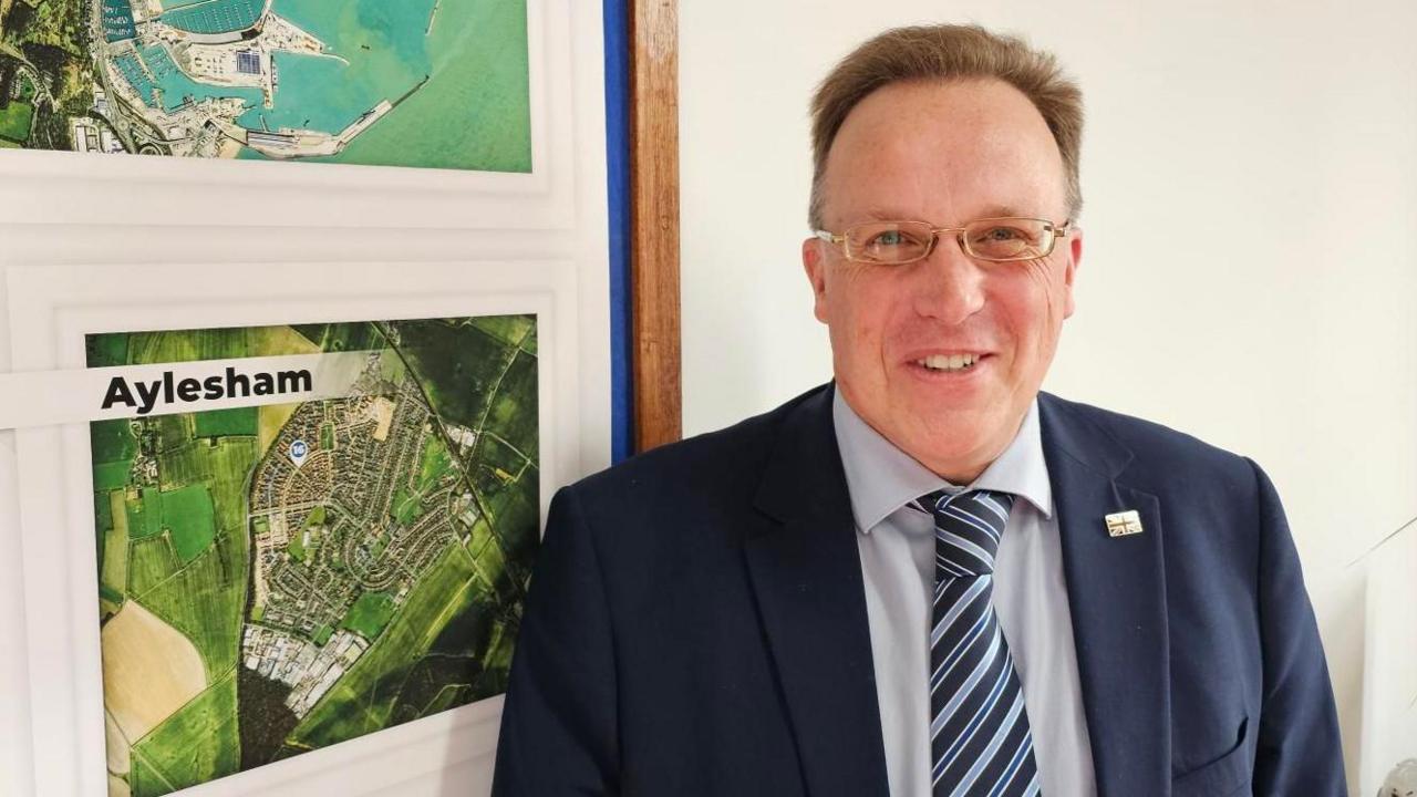 Charles Woodgate stands beside a map of part of his ward, Aylesham.