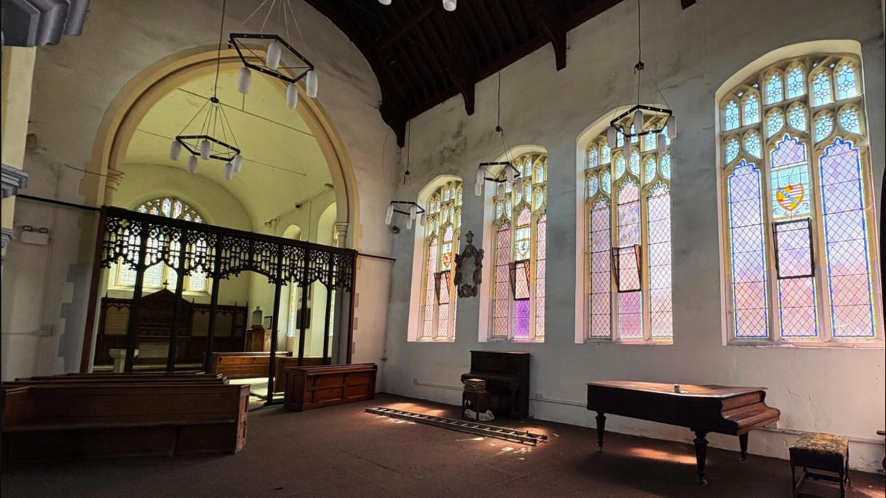 The interior of St Peter's Church, showing the altar and side windows, and a baby grand piano