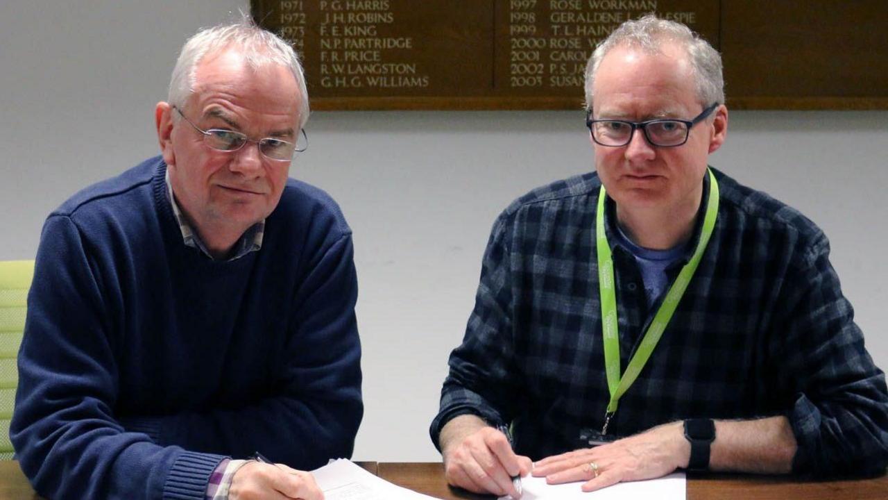 Jeremy Hilton with resources cabinet member Declan Wilson, sat at a desk while reading through documents with a pen in hand