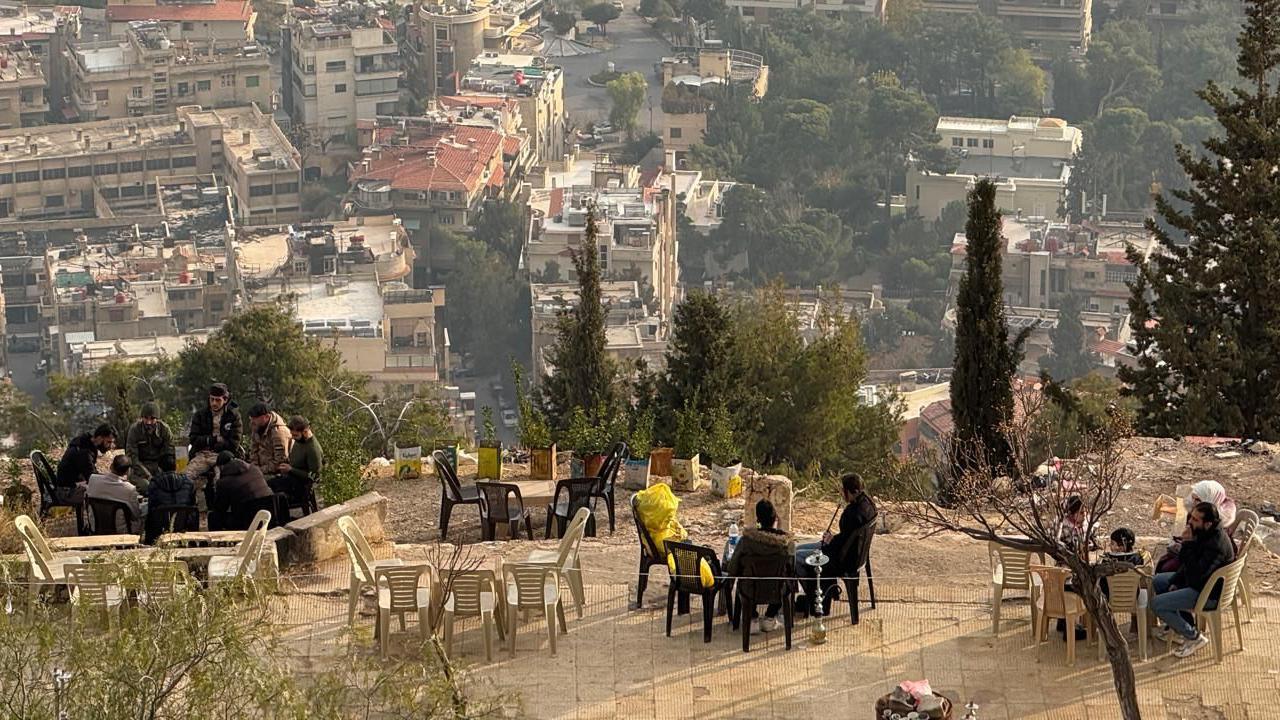 Syrians sitting in groups on a terrace overlooking Damascus