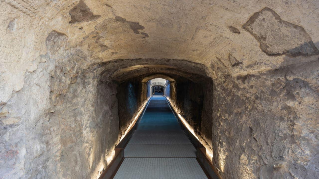 An ancient tunnel with a long lit path.