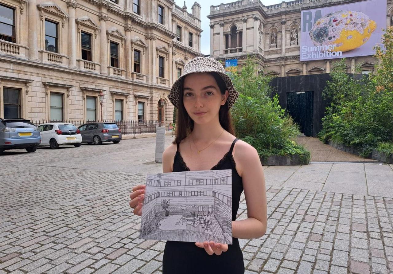 Cristiana Borg holding one of her drawings as she stands outside the Royal Academy of Arts