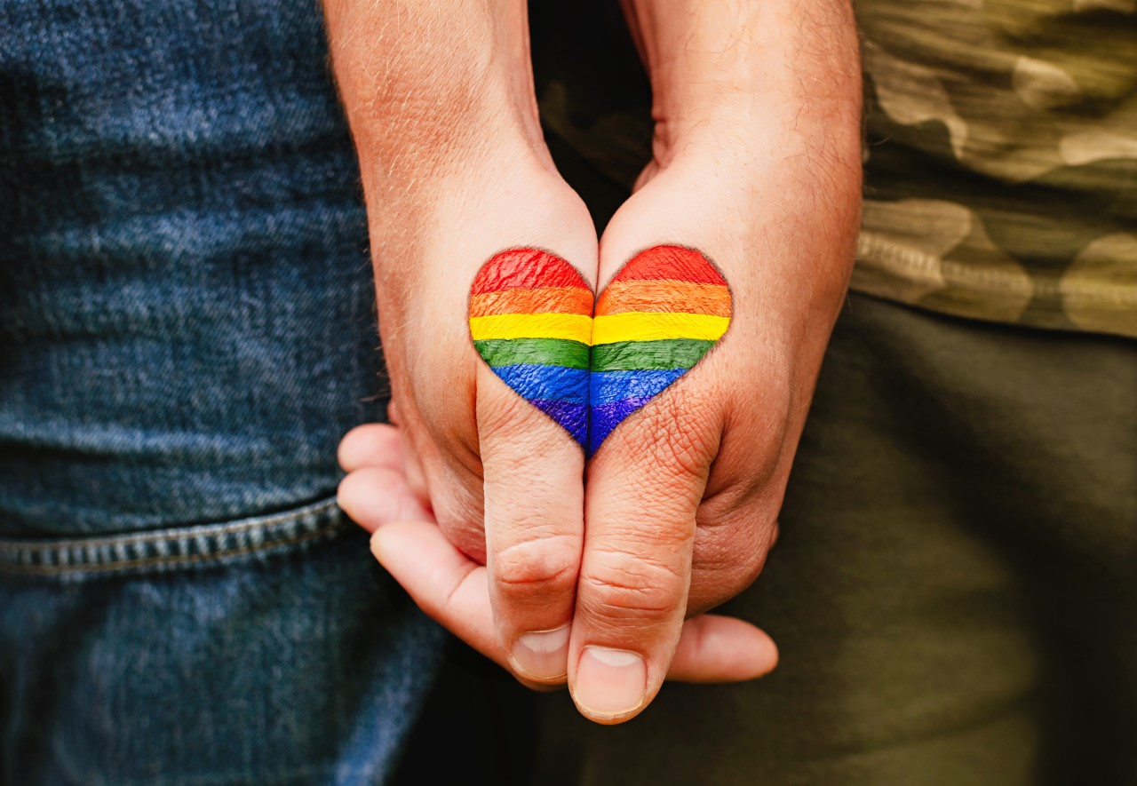 Rainbow heart drawing on hands.