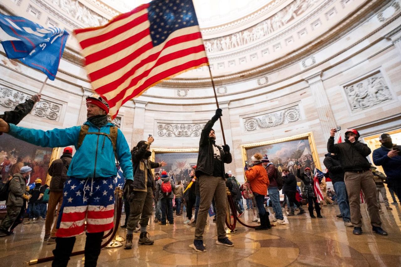 Protesters fill the Rotunda of the US Capitol building waving a US flag